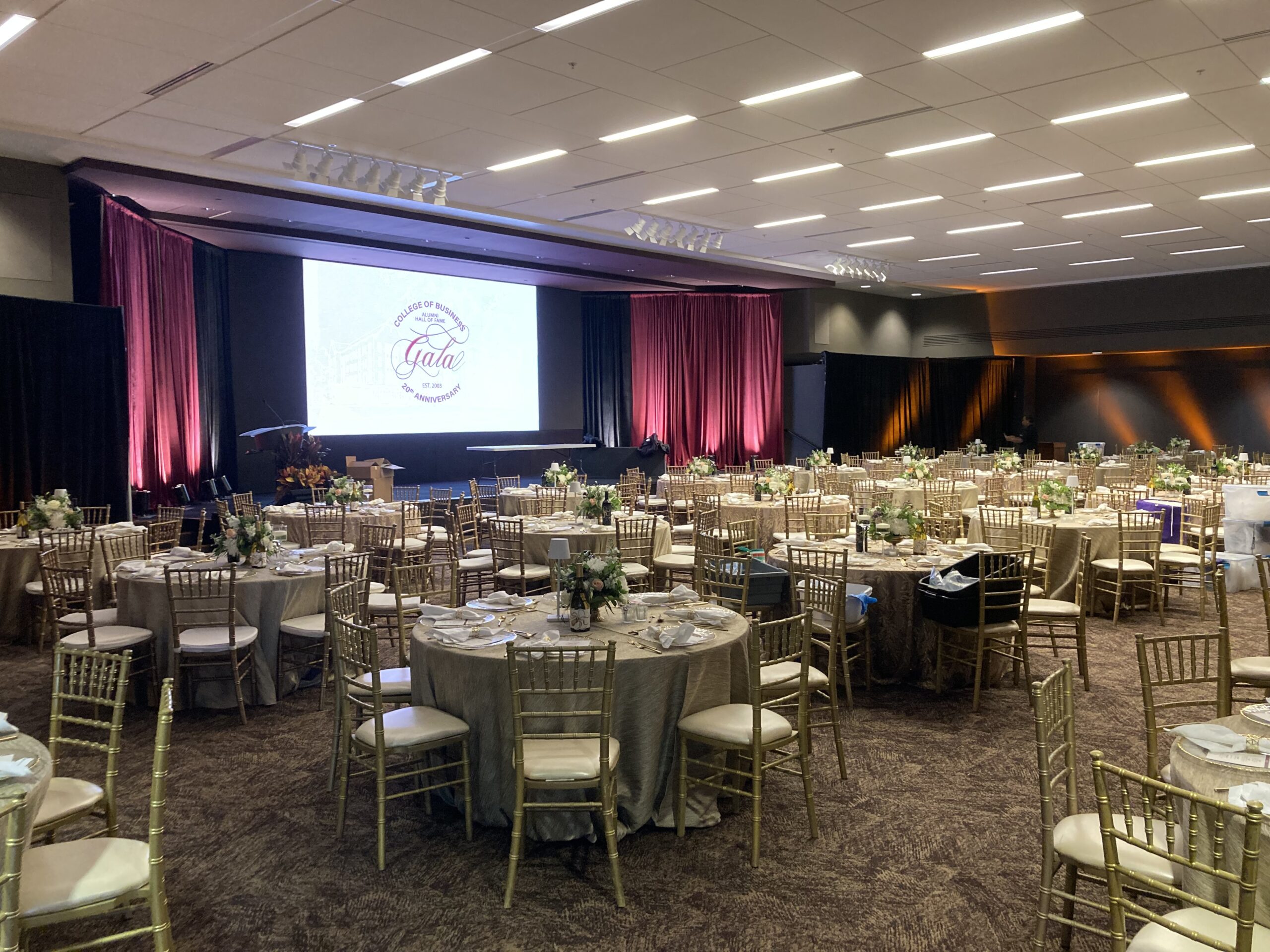 Room 208 arranged for a banquet with the auditorium video wall and stage visible