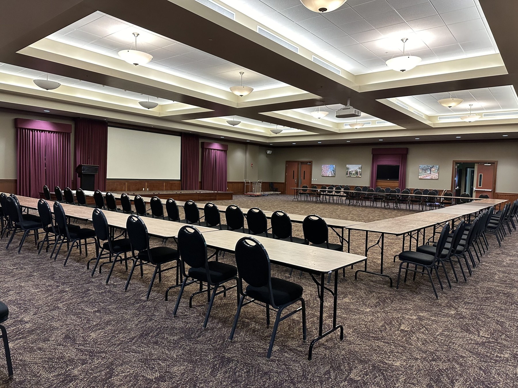 Room 108 arranged with tables around the presentation space